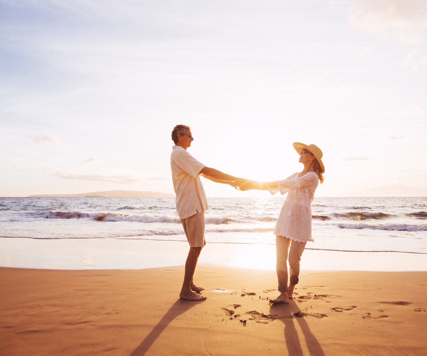 Happy Romantic Middle Aged Couple Enjoying Beautiful Sunset on the Beach. Travel Vacation Retirement Lifestyle Concept.